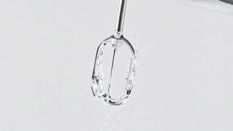 Ilustração 3D mostrando a lâmina de um mixer sendo limpa sob um fluxo de água, demonstrando o processo de como limpar um mixer corretamente.